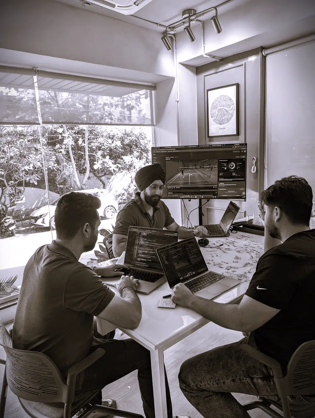 The Kreeda team working around a table of laptops, with a Kreeda analysis on the screen behind them. Ramandeep Singh sits in the centre.